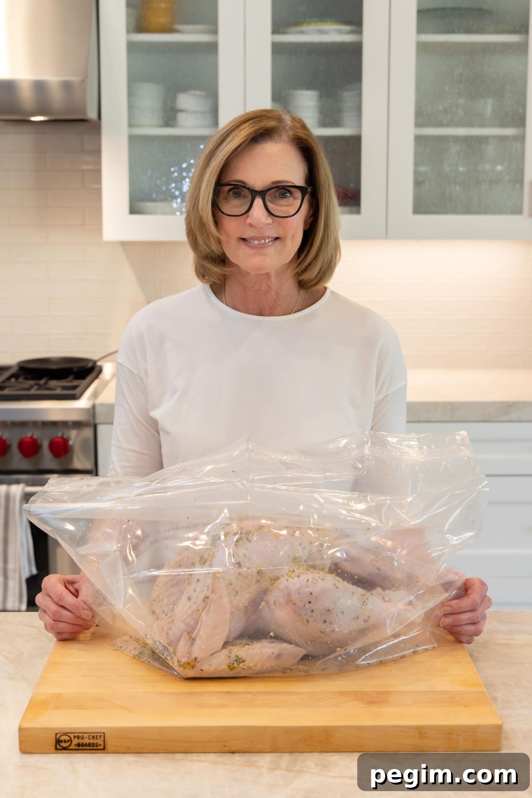 A turkey in a brining bag covered with herbs, citrus, and salt on a kitchen counter.