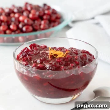 Deep red whole berry cranberry sauce in a glass bowl.