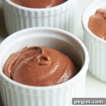 Three white ramekins of chocolate mousse.