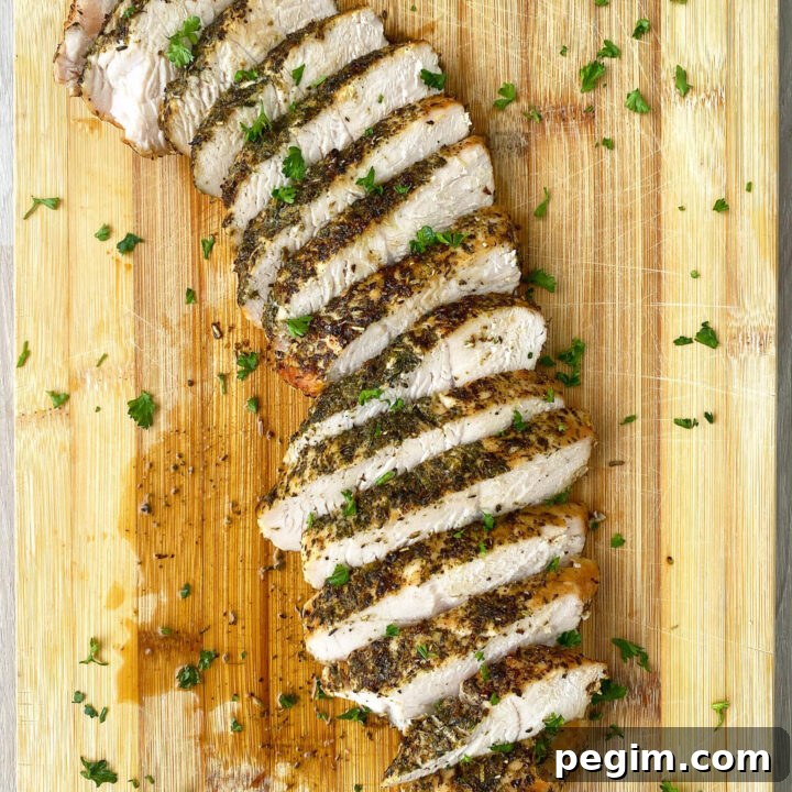 overhead shot of sliced, cooked turkey breast tenderloin on a wooden cutting board