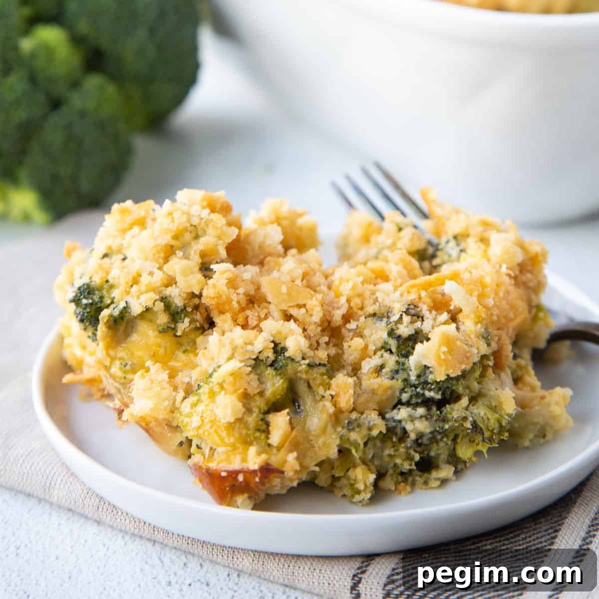 scoop of cheesy velveeta broccoli casserole topped with ritz cracker crumbs on a white plate.