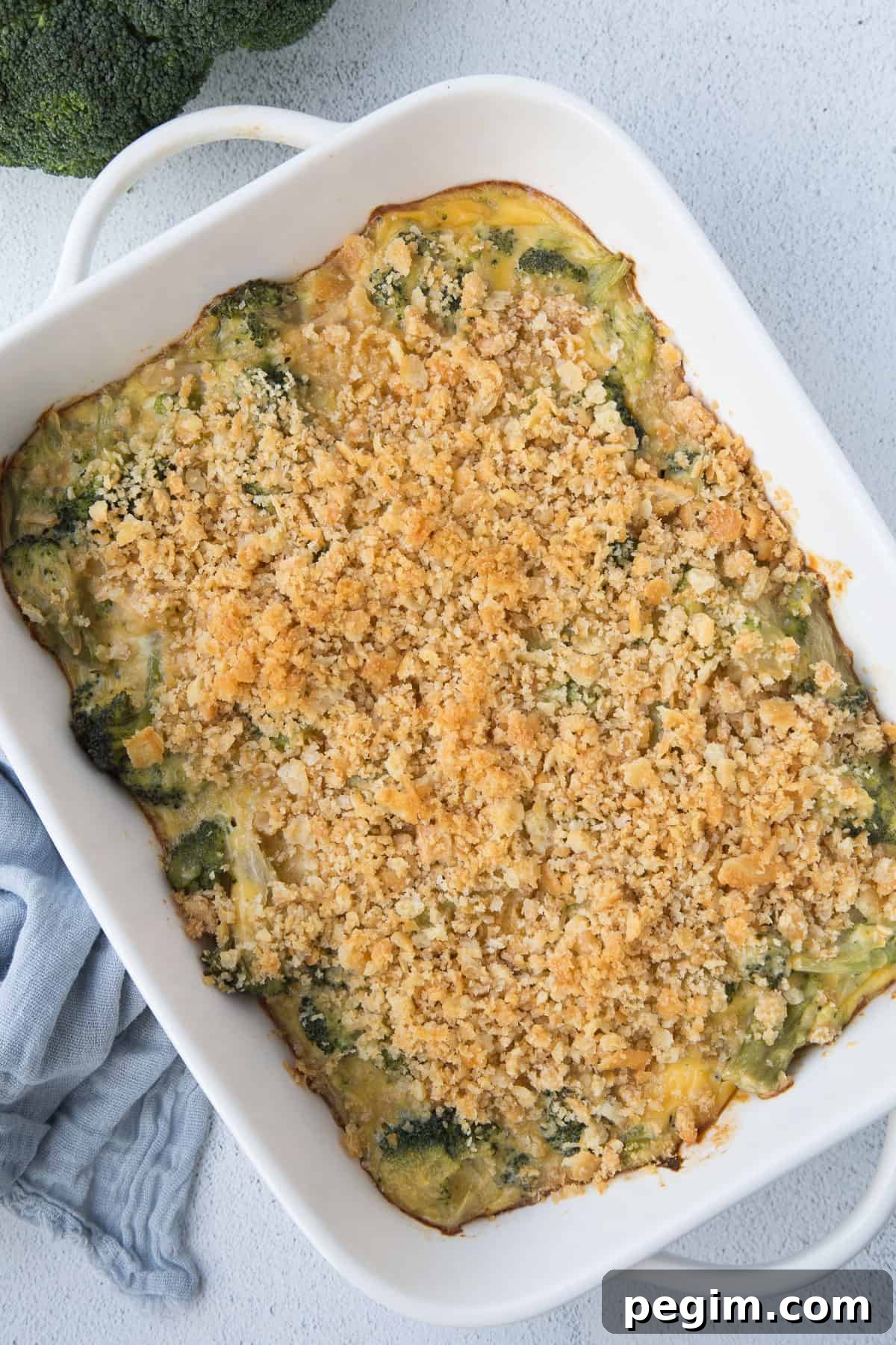 velveeta broccoli casserole topped with ritz cracker crumbs in a white casserole dish.