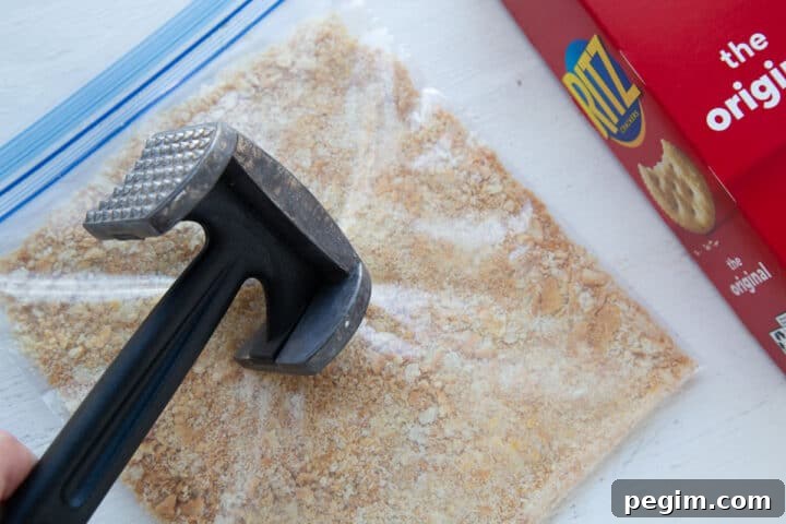 meat mallet pounding a plastic bag filled with ritz cracker crumbs.