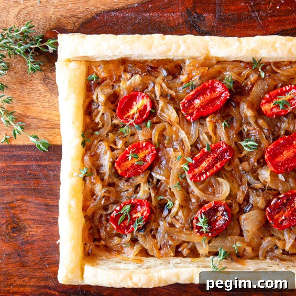 A puff pastry tart of caramelized onions and mushrooms topped with tomatoes.