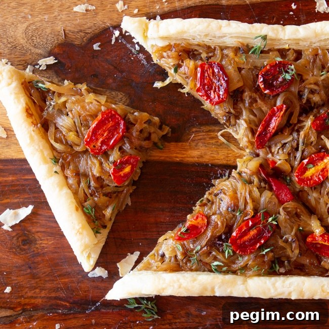 A French Onion Tart on a cutting board, sliced into 4 pieces.