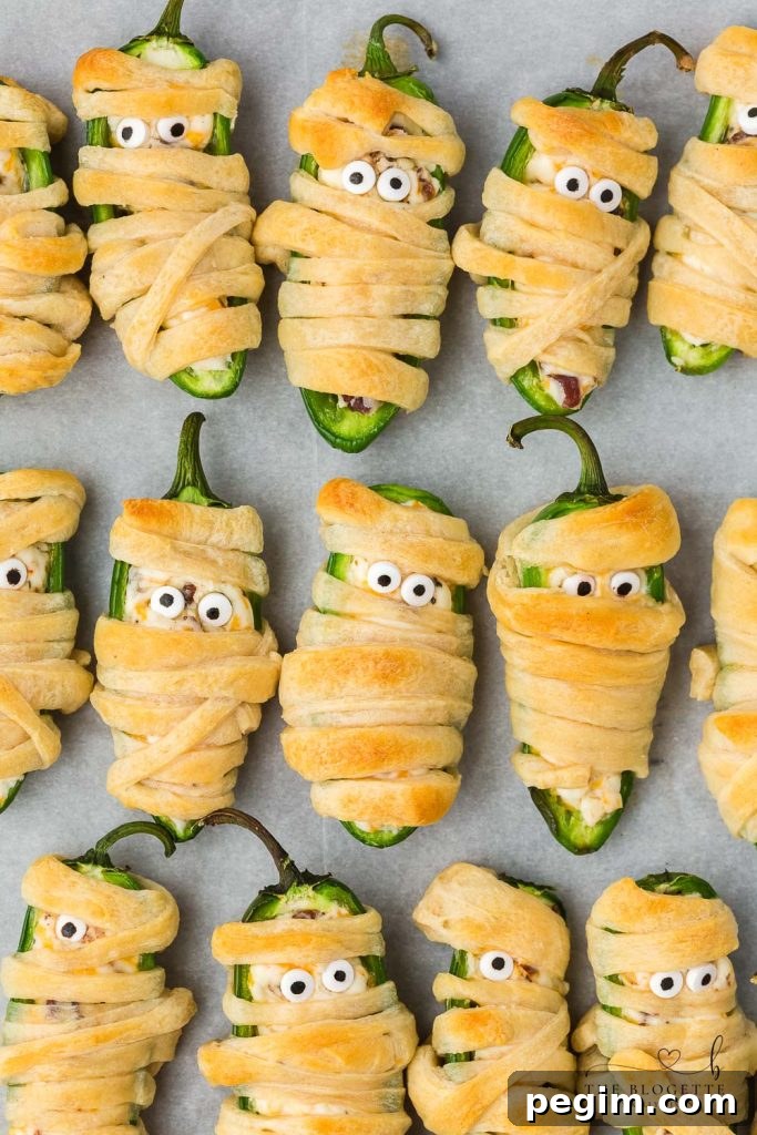 Halloween Jalapeño Popper Mummies are adorably spooky jalapeños, filled with a cream cheese mixture, wrapped in crescent dough, and baked!