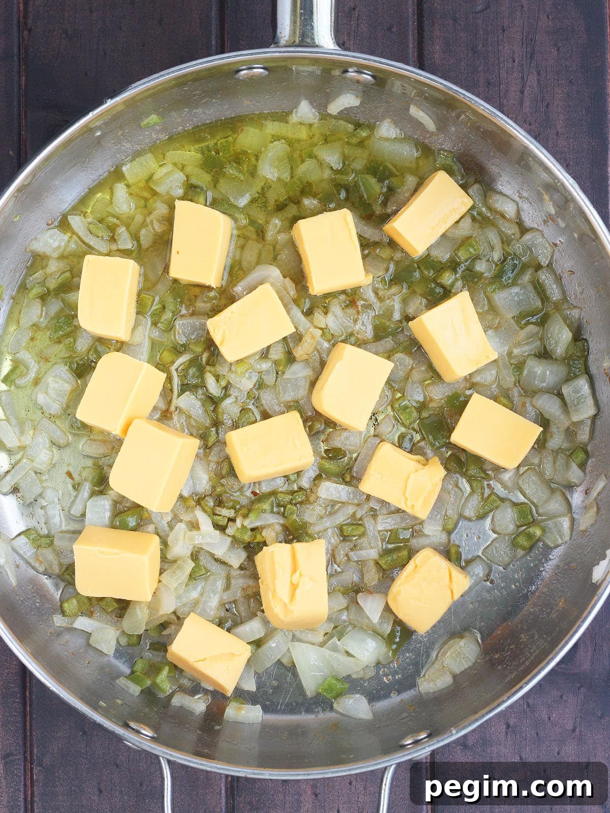 cut up pieces of Velveeta cheese and sauteed vegetables in a large stainless steel skillet