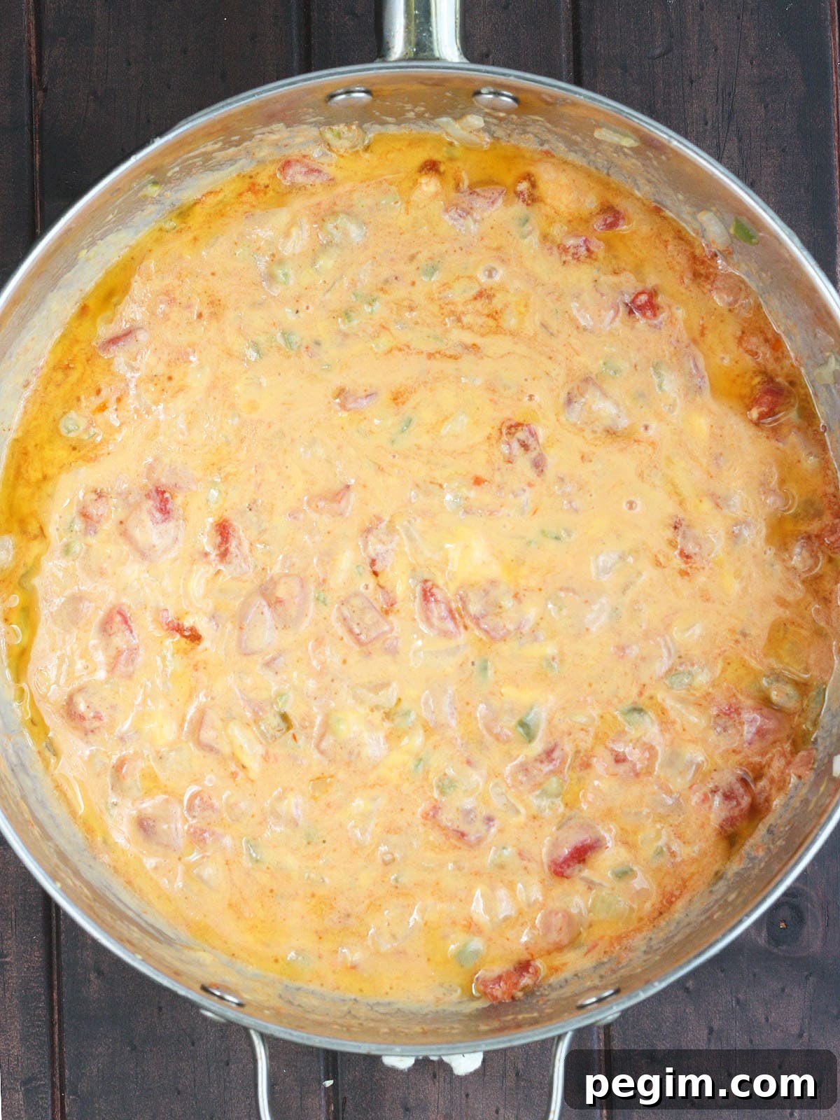 melted cheese, rotel tomatoes and vegetables in a large stainless steel skillet