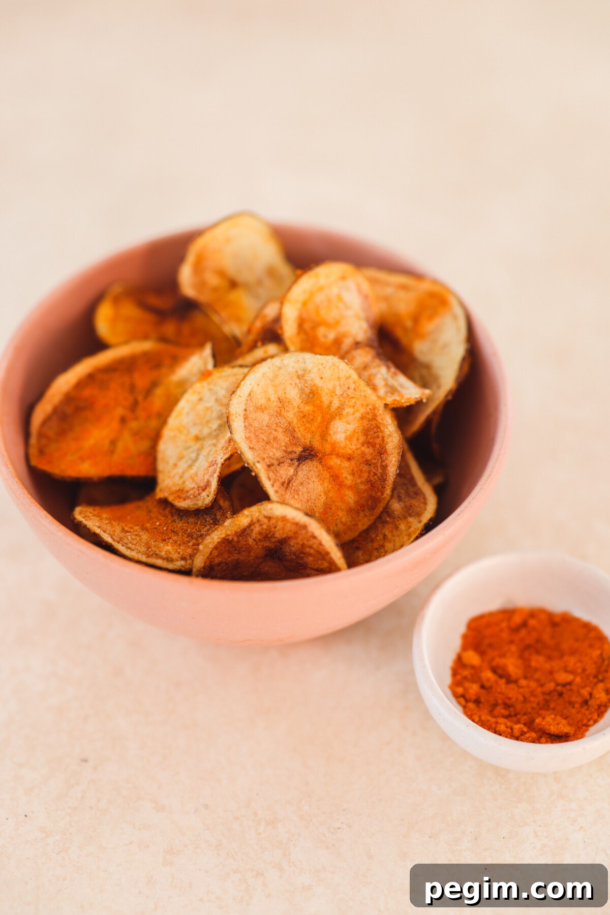 a bowl of spicy potato chips next to a bowl of seasoning 