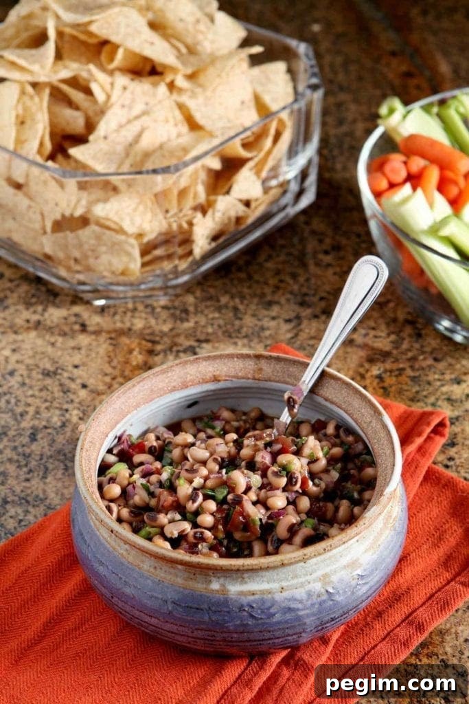 Bowl of Black Eyed Pea Dip served with chips and vegetable sticks 