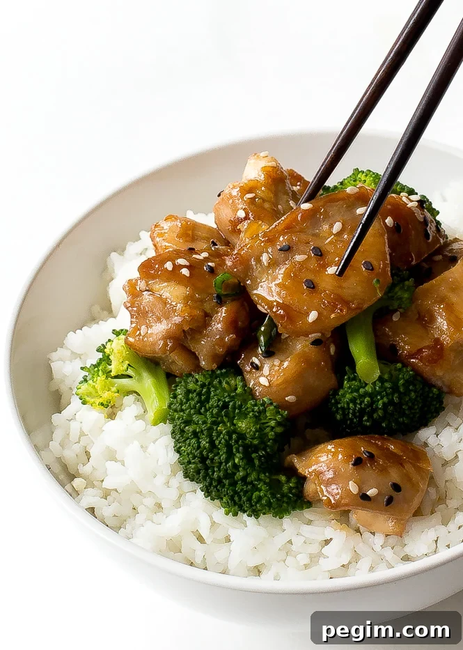 White bowl with chicken, broccoli, and white rice with chopsticks