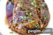 A sliced balsamic pork loin with glaze sitting on a large white plate.