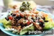Sweet pork sitting on a blue plate with a flour tortilla and jar of dressing in the background.