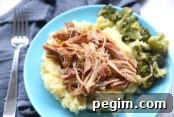 A blue plate holding a serving of crazy good pork and potatoes with green beans and a fork to the side