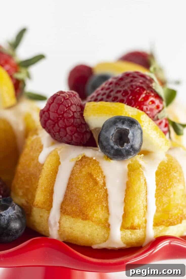 Mini lemon bundt cakes on a red cake plate with fresh fruit.