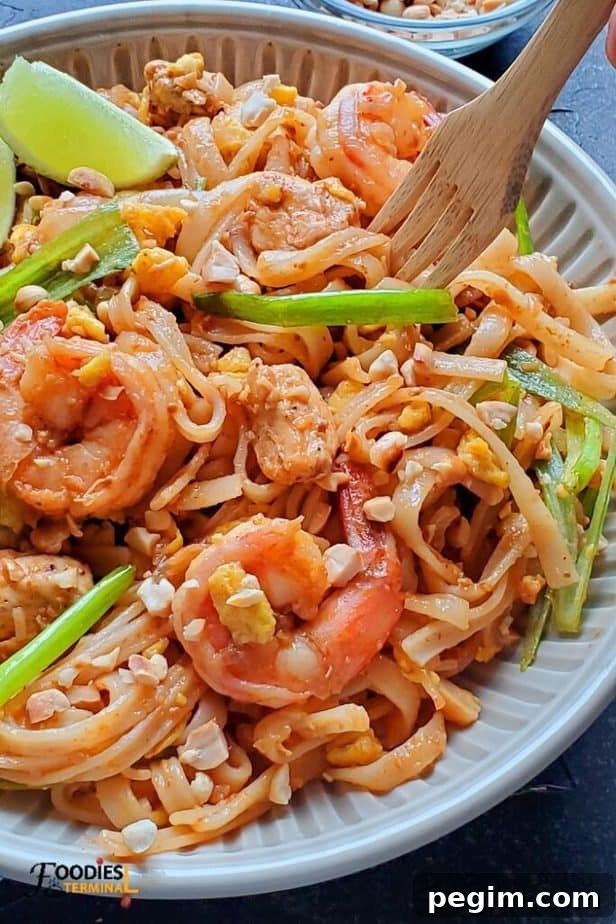 instant pot pad thai with chicken and shrimps in a bowl with a wooden fork