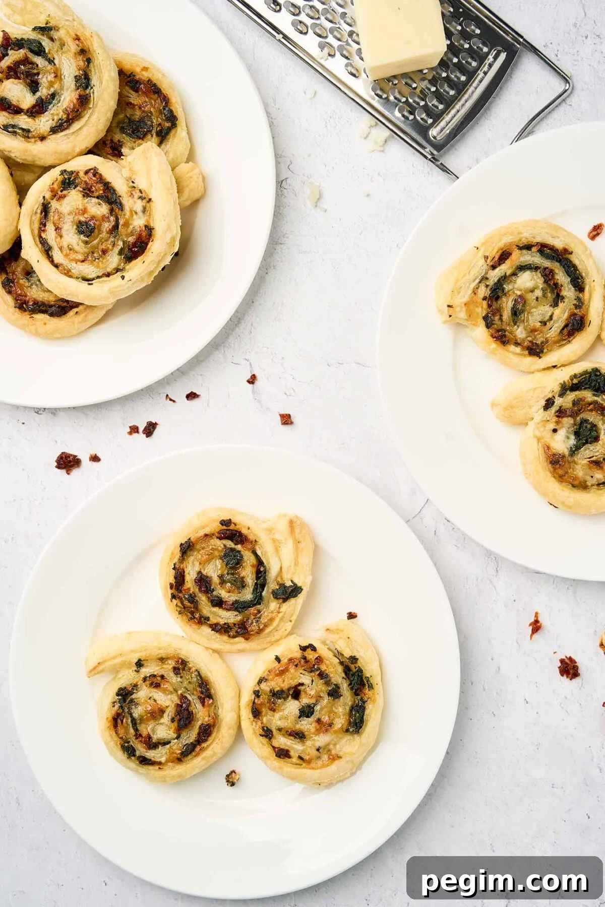 Plated servings of spinach pinwheels made with puff pastry, spinach, fontina cheese, and sun-dried tomatoes.