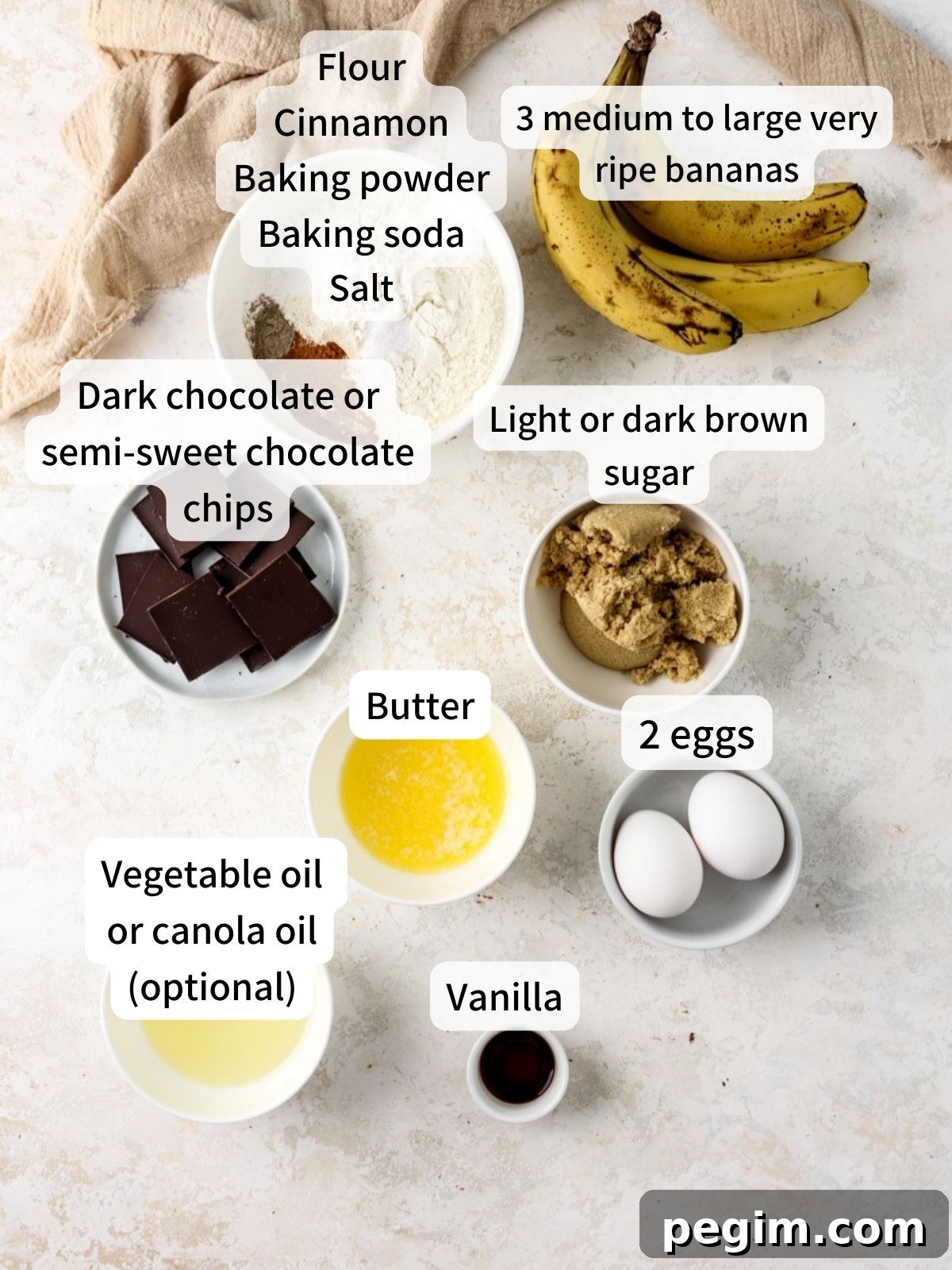 Labeled ingredients needed to make chocolate banana muffins laid out on a table. 