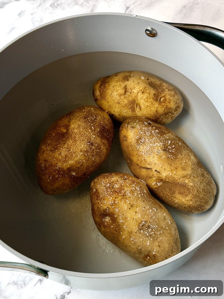 Whole russet potatoes, unpeeled in a pot of water with salt.