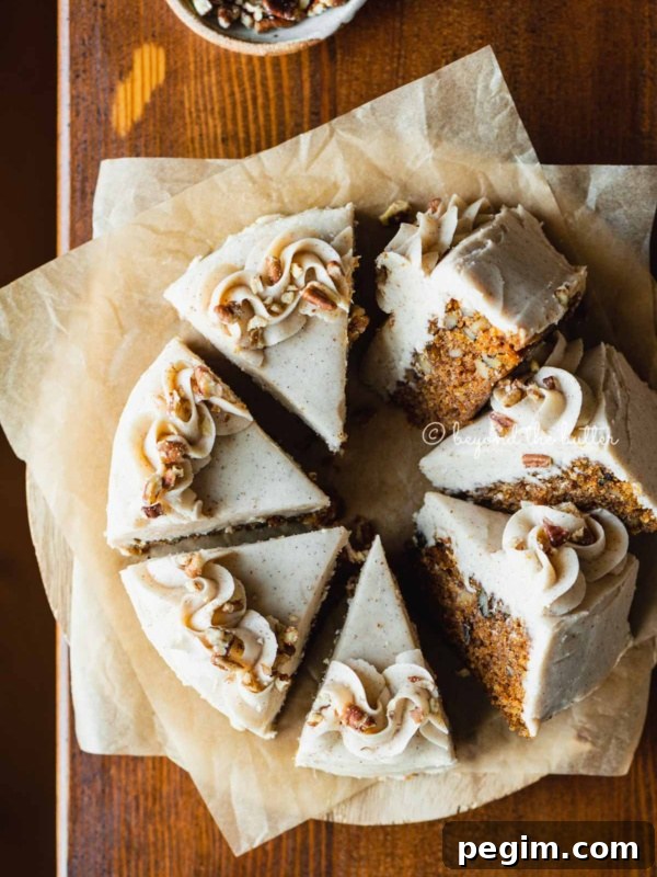 Overhead image of single layer carrot cake frosted on parchment paper and placed on a wood dining room table.