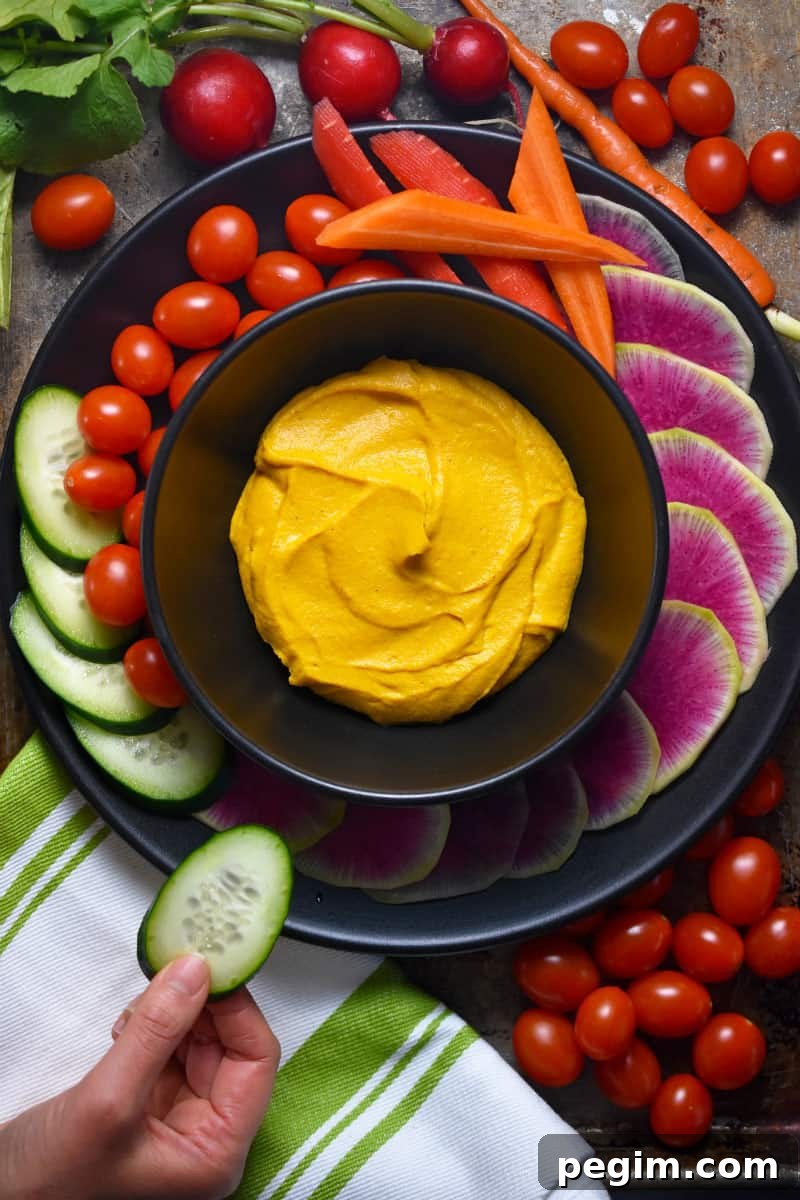 An overhead shot of a colorful platter of vegetables surrounding a bowl of vegan and Whole30 sweet potato and cashew dip.