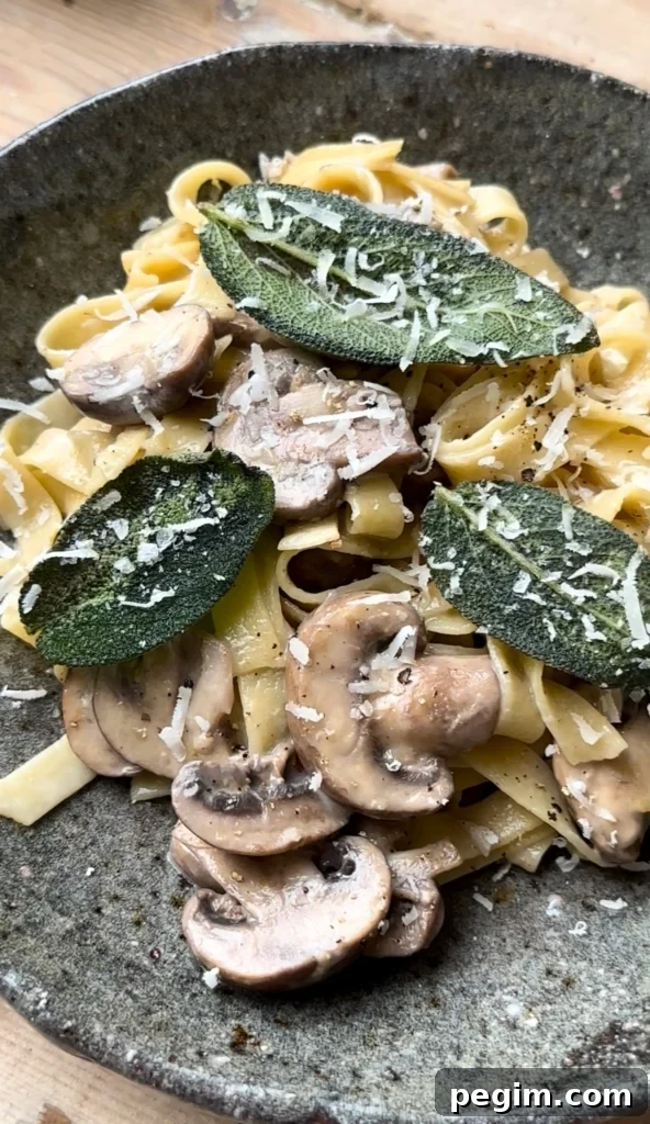 Up close image of a bowl of pasta topped with mushrooms, cripsy sage laves, and shreeded parmesan cheese.