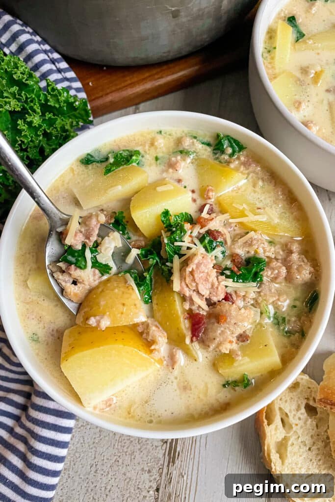 Best Olive Garden Zuppa Toscana Soup in a white serving bowl topped with bacon bits and fresh parsley.  