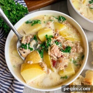 Best Olive Garden Zuppa Toscana Soup in a white serving bowl topped with bacon bits and fresh parsley.