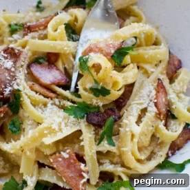 A closeup of a plate of pasta carbonara without cream with a fork in it