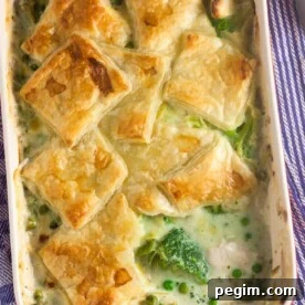 A chicken and leek pie with squares of puff pastry on top in a red baking dish