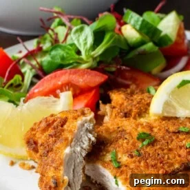 Panko chicken breast on a white plate with salad