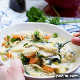 Someone holding and eating a bowl of crockpot chicken gnocchi soup