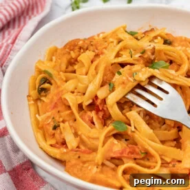 A white dish of creamy chorizo pasta with a fork in it