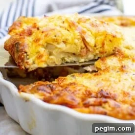 Someone lifting a piece of crustless quiche from a white quiche dish