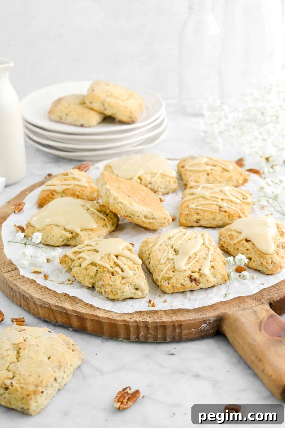 side shot of maple pecan scones on wood serving board with flowers and stacked plates