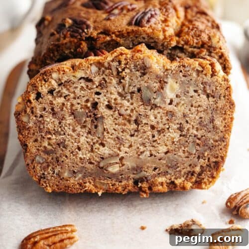 A close up of a slice of pecan banana bread on parchment paper.
