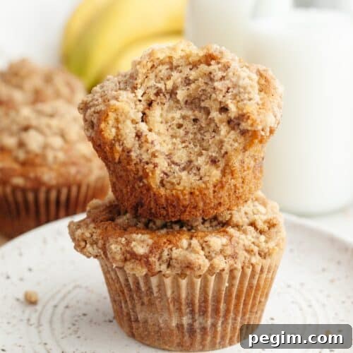 A stack of two banana coffee cake muffins, one has a bite taken out of it.