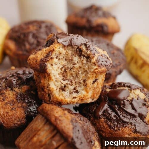 Banana muffins in a pile, one with a bite taken out of it.
