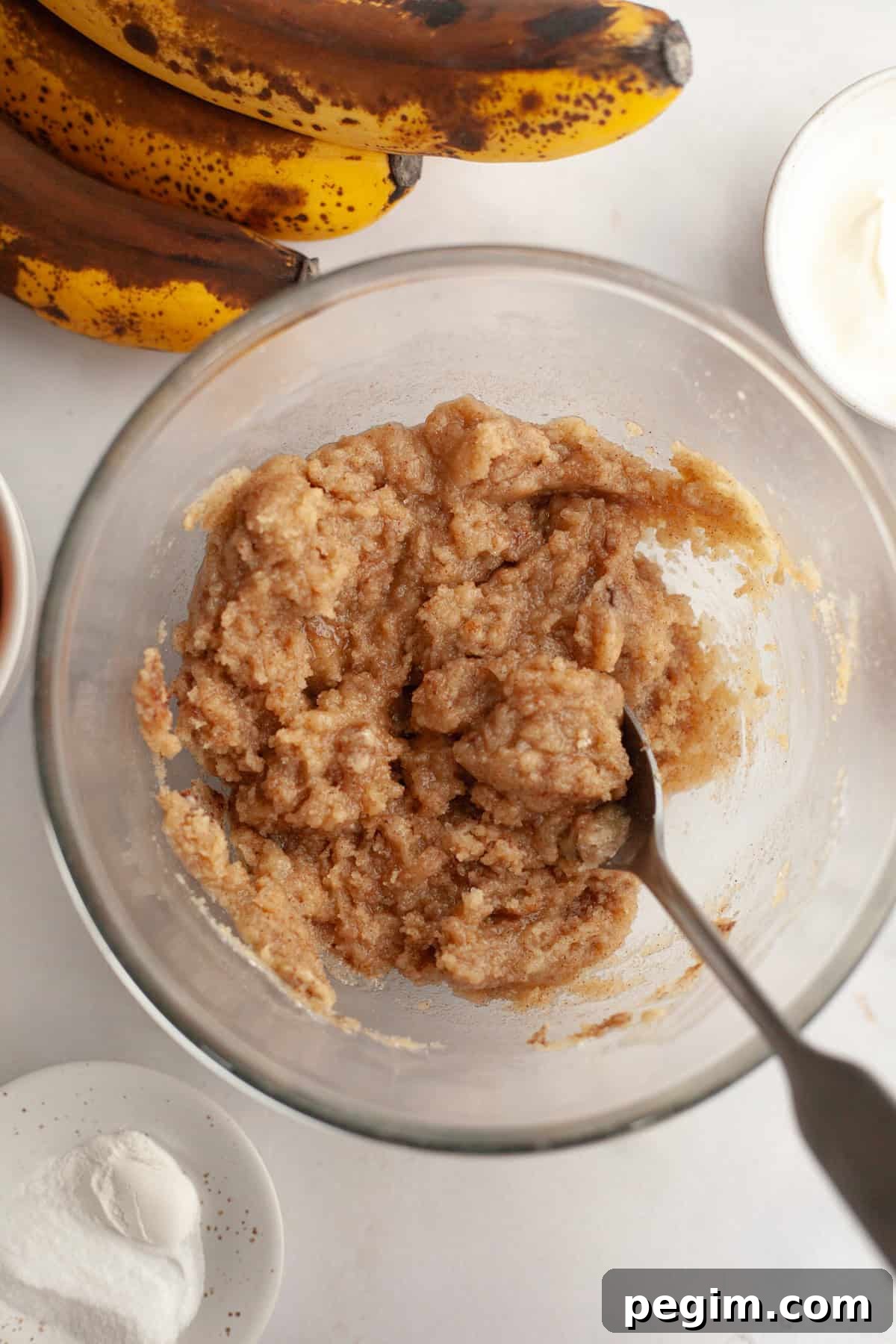 A glass bowl with a spoon and streusel topping in it.