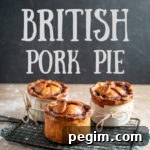 3 handmade British pork pies cooling on a wire rack over a wooden board