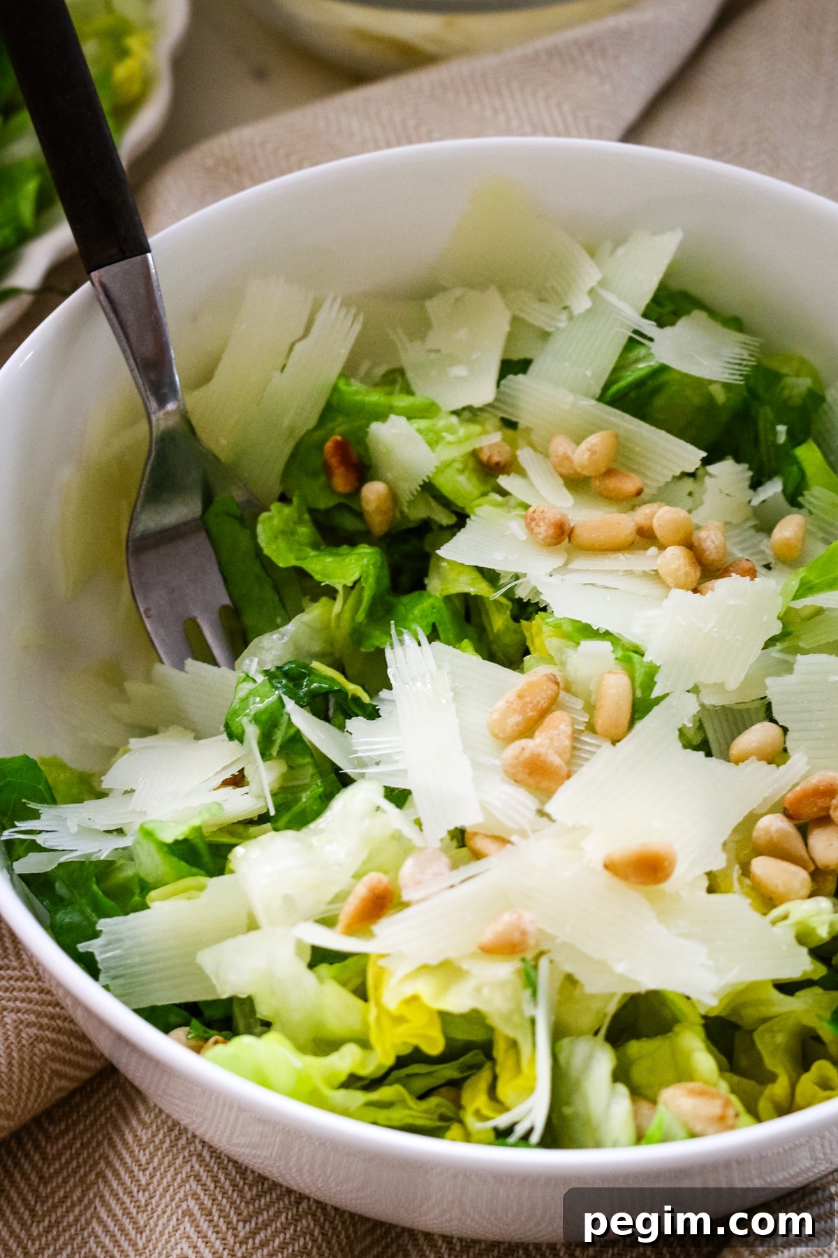 Romaine salad in a white bowl with a fork in it.