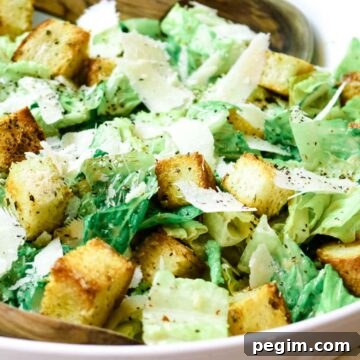 white bowl with caesar salad on top of white kitchen towel