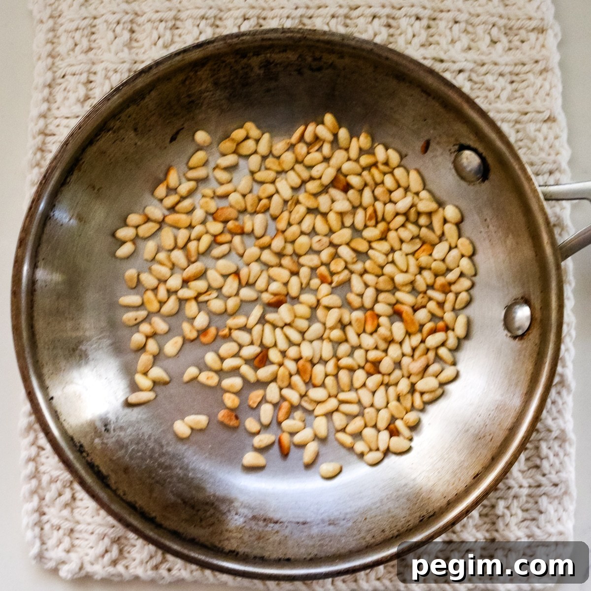 Nuts being toasted in a pan.