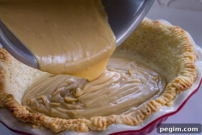 filling a blind baked pie crust with butterscotch filling.