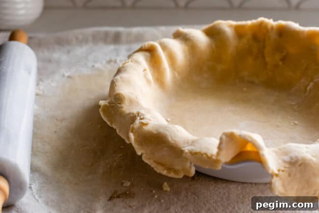 raw pie dough rolled out in a pie pan, ready to blind bake.