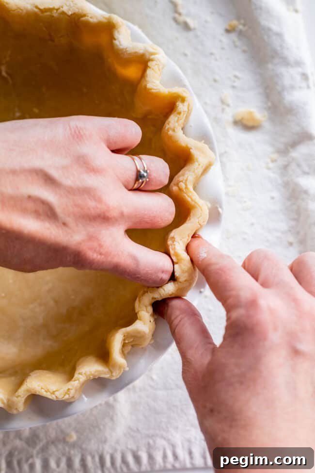 fluting the edges of pie crust to blind bake.