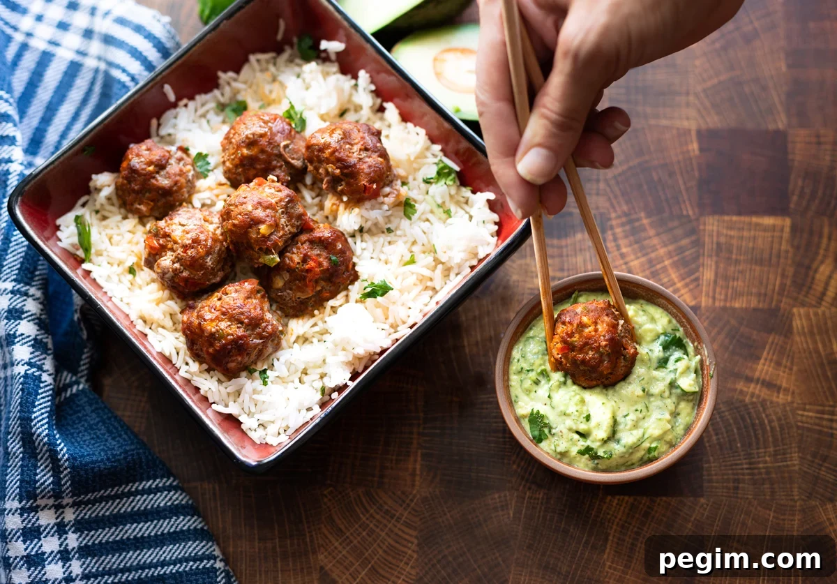 person dipping a turkey meatball in avocado sauce. 