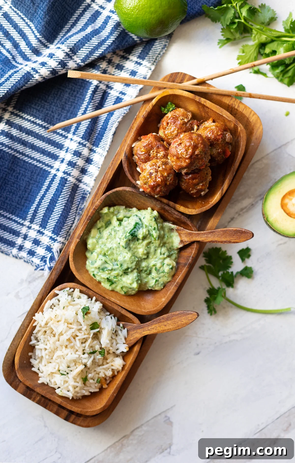 Rice, avocado sauce, and meatballs in a serving dish with chopsticks. 