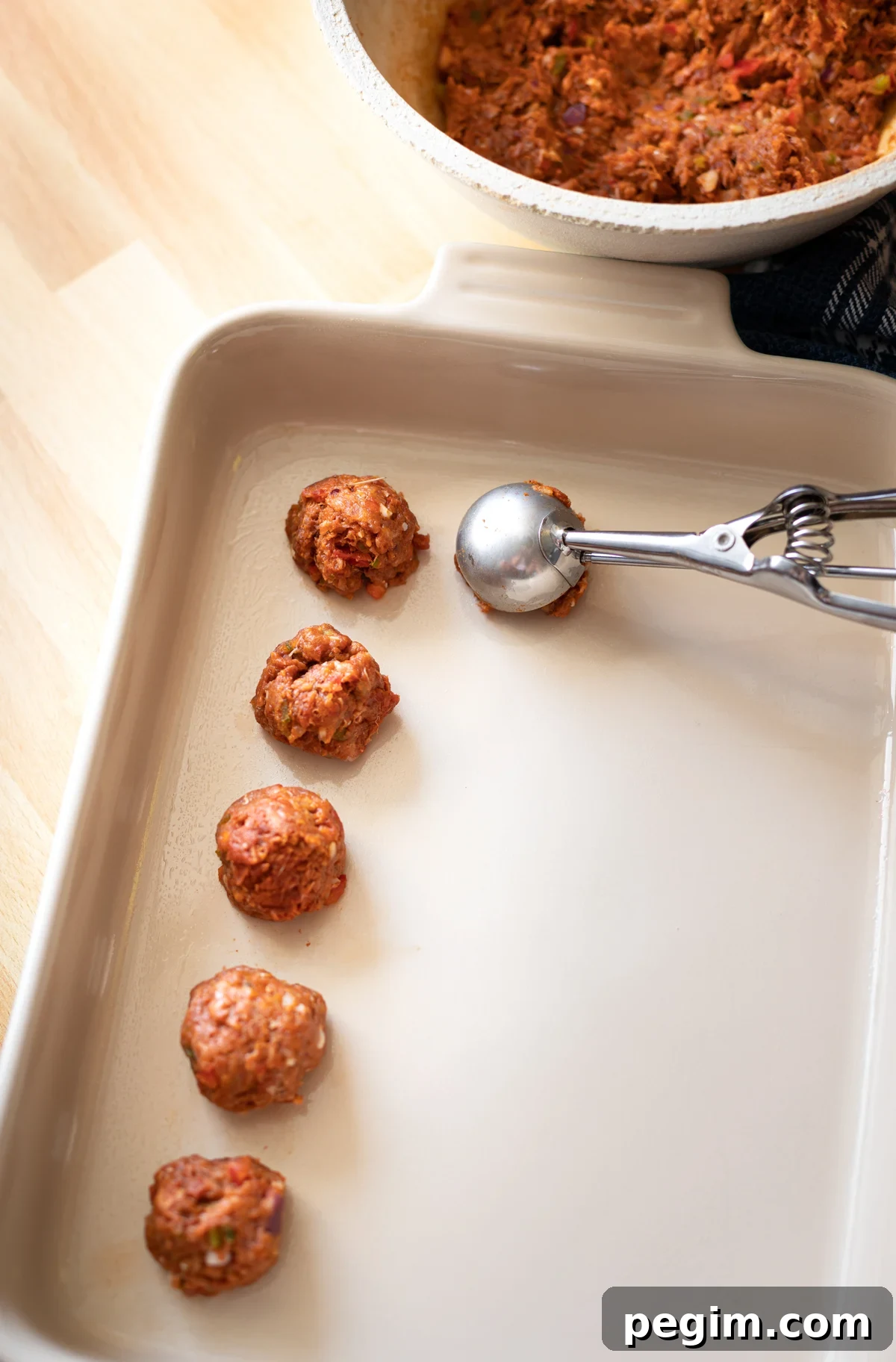 Scoop of turkey and chorizo mixture being placed in a baking dish. 