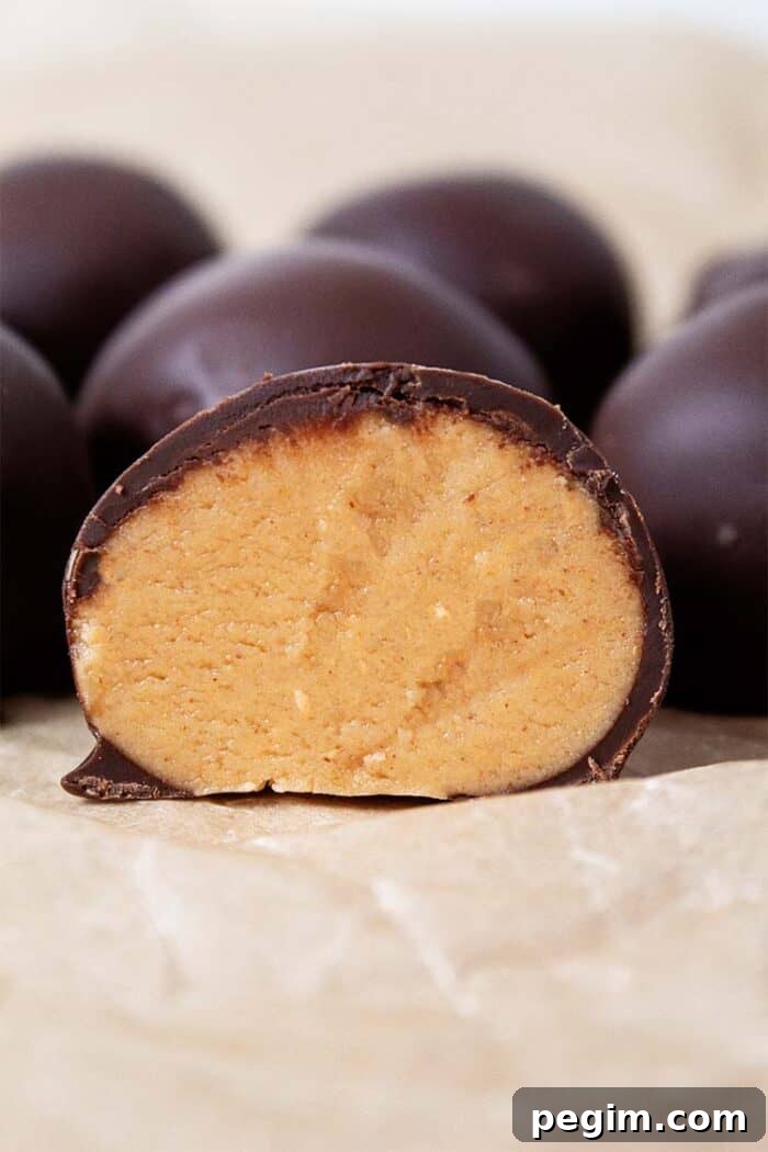 sideview of keto peanut butter balls on countertop and one of them is cut in half revealing the peanut butter interior, ready to serve
